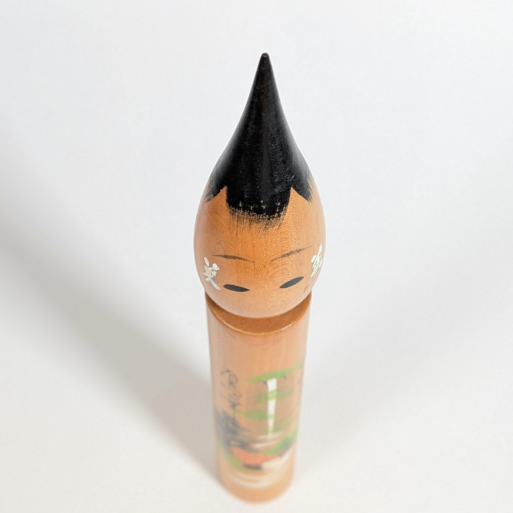 Vue plongeante du dessus d’une poupée japonaise fude kokeshi en bois, visage et coiffure laquée
