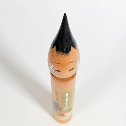 Vue plongeante du dessus d’une poupée japonaise fude kokeshi en bois, visage et coiffure laquée