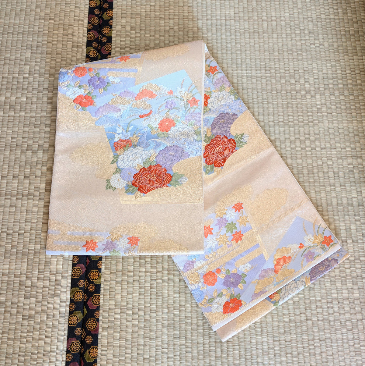 Fukuro obi japonais en soie déployé sur tatami, décor bleu ciel et or de paon, pivoines, érables et fleurs