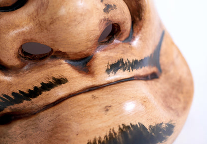 Gros plan sur la bouche fermée et la moustache noire d’un masque japonais Beshimi en céramique, inspiré du théâtre Nô traditionnel