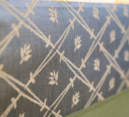 Gros plan sur la soie bleue brodée du chūberi d’un kakejiku japonais, motif végétal et tissage traditionnel