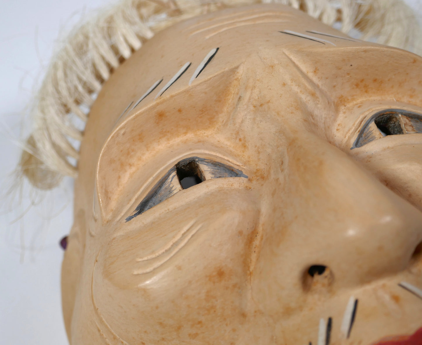 Détail sur les yeux peints et la finesse sculpturale d’un masque Nô type Kōshi-jō, expression tendue et mélancolique.