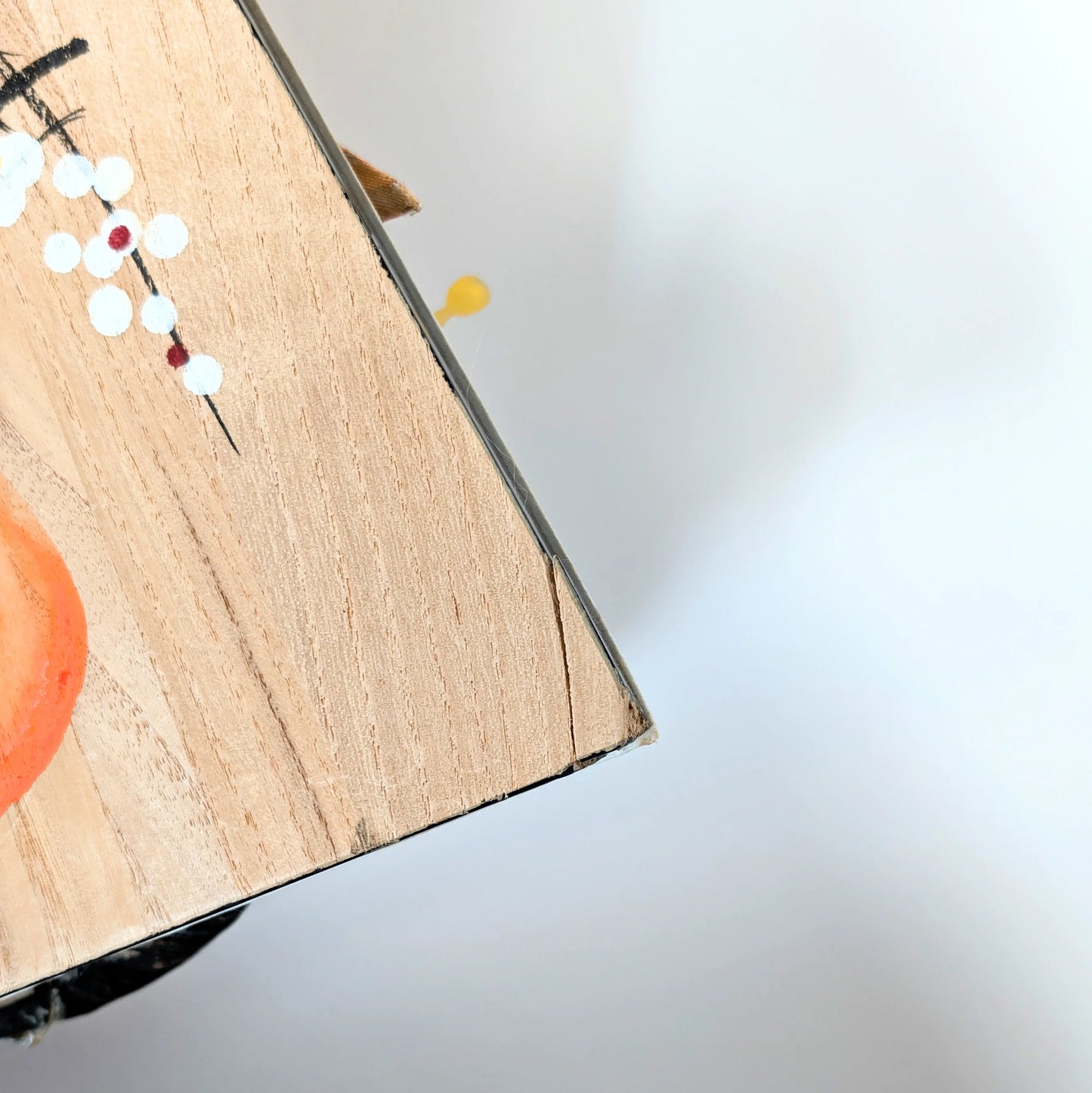 Coin légèrement abîmé au dos d’une hagoita japonaise ancienne, trace du temps sur bois peint