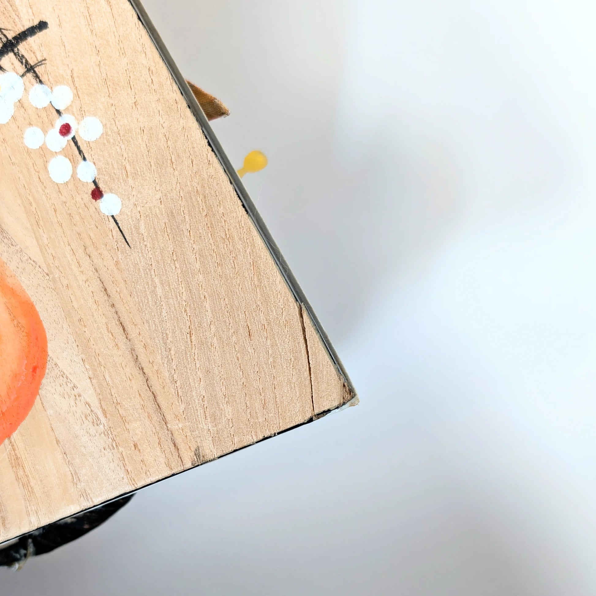 Coin légèrement abîmé au dos d’une hagoita japonaise ancienne, trace du temps sur bois peint