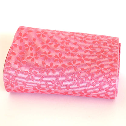 Obi hanhaba rose à motifs sakura, présenté roulé.
