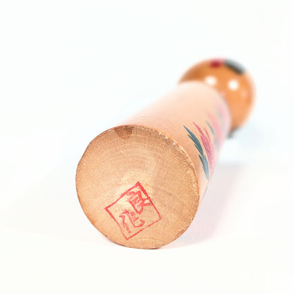 Cachet rouge hanko 良作 sous la base d’une kokeshi japonaise signée Ryosaku, poupée en bois artisanale de collection.