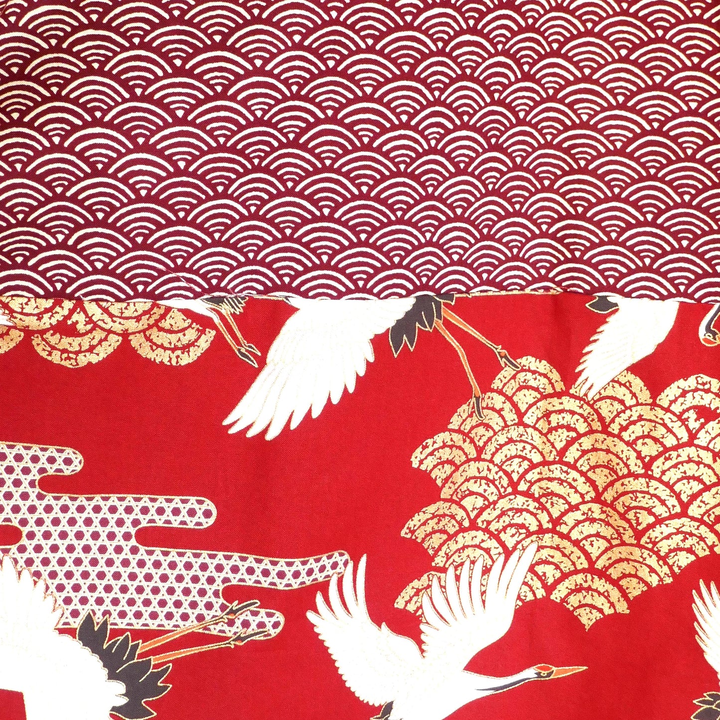 Détail de l’empiècement dos du haori Akane Tsuru, avec grues blanches volant au-dessus de vagues dorées sur fond rouge profond.