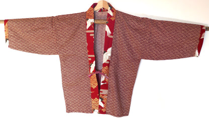 Haori Akane Tsuru vu de face, motifs vagues seigaiha rouge, fermé par un obijime obihimo assorti, avec col à motifs de grues japonaises et fond rouge vif.