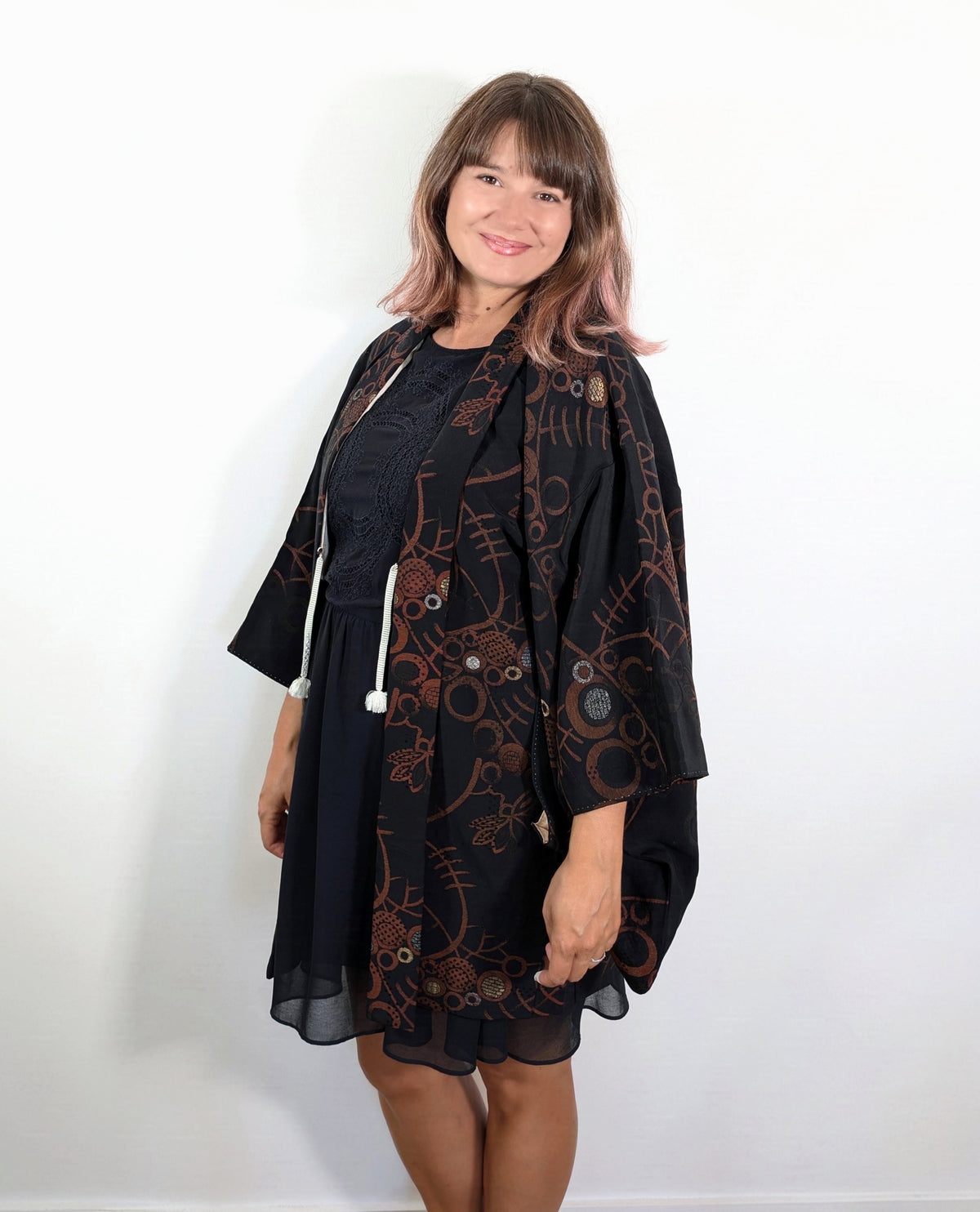 Femme portant un haori japonais vintage en brocart de soie noire, aux motifs floraux cuivrés et cercles dorés et argentés.