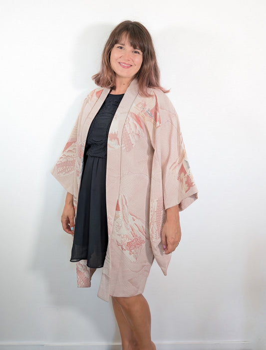 Haori femme en soie rose saumon porté comme veste kimono japonaise, avec motifs de vagues et paysages du Tōkaidō