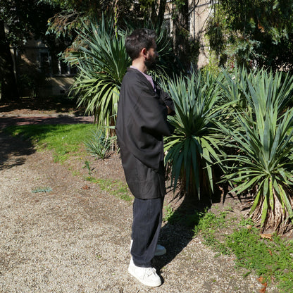 Tôma de profil en veste kimono traditionnelle haori vintage japonais en soie marron grisé, dans un parc à Paris.