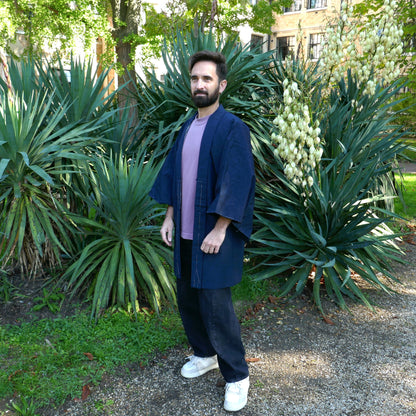Haori homme vintage en soie bleu indigo porté par Tôma de face dans un jardin