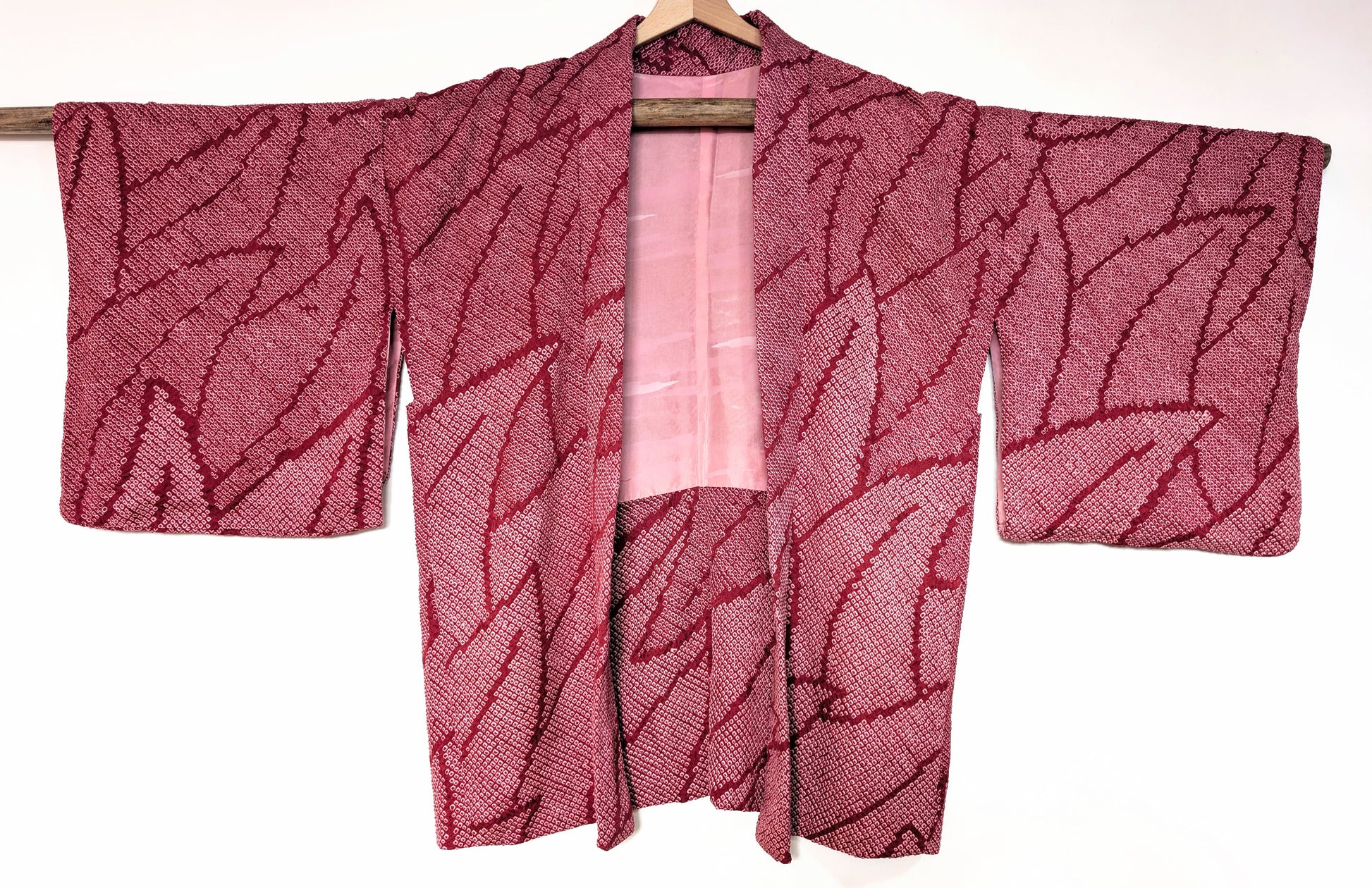 Haori japonais ancien pour femme, 100% soie, shibori rose fuchsia à motif feuillage, vue de face sur cintre.