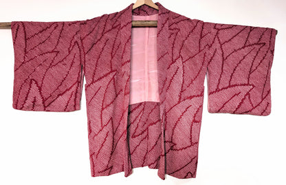 Haori japonais ancien pour femme, 100% soie, shibori rose fuchsia à motif feuillage, vue de face sur cintre.