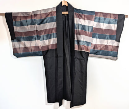 Haori japonais ancien en soie noire ouvert, laissant apparaître la doublure traditionnelle rayée
