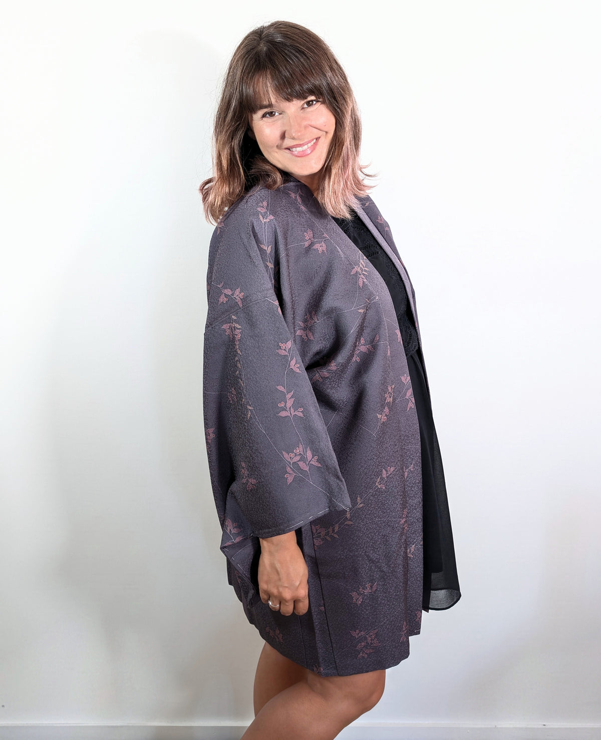 Femme portant un haori japonais en soie violet grisé à motif nanten rose, veste kimono traditionnelle