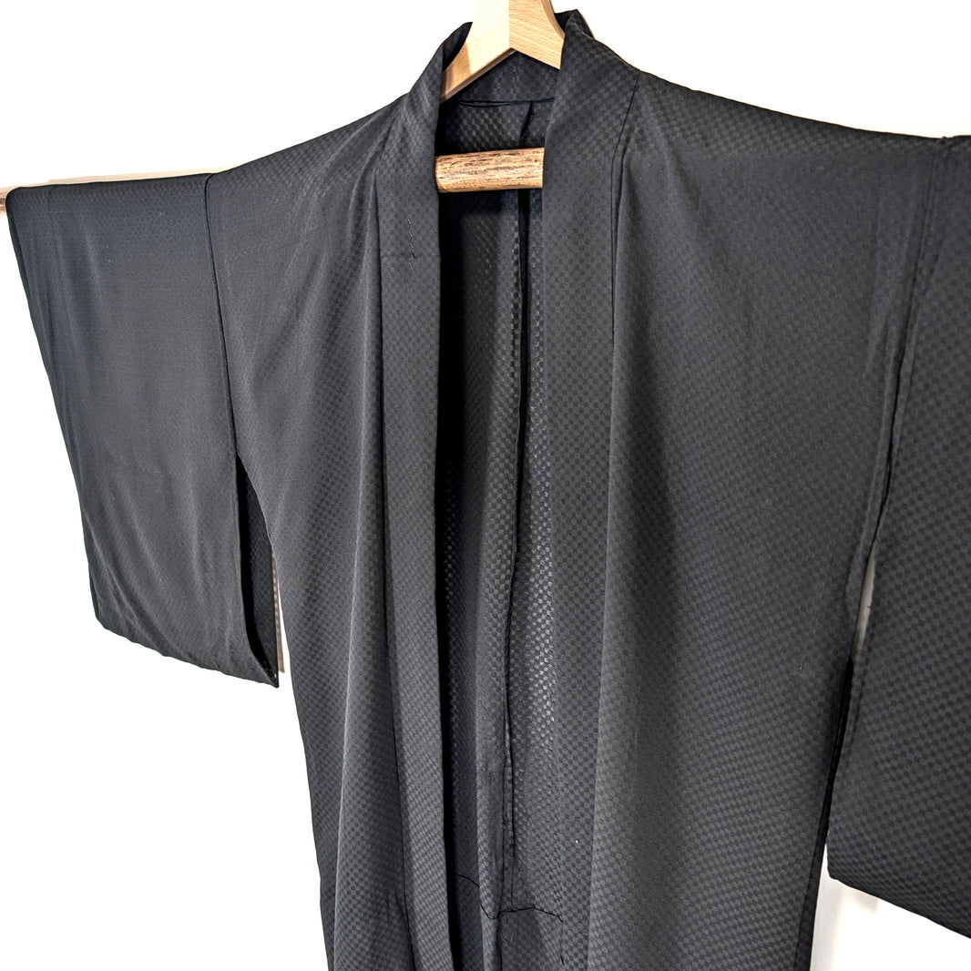 Haori japonais léger en soie noire monsha à motif ichimatsu, détail du col et des larges manches traditionnelles.