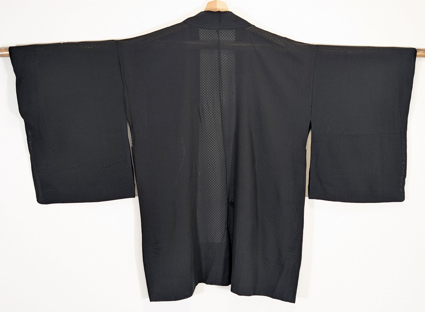 Vue de dos d’un haori japonais léger de type usubaori en soie noire monsha, étoffe transparente à damier ichimatsu.