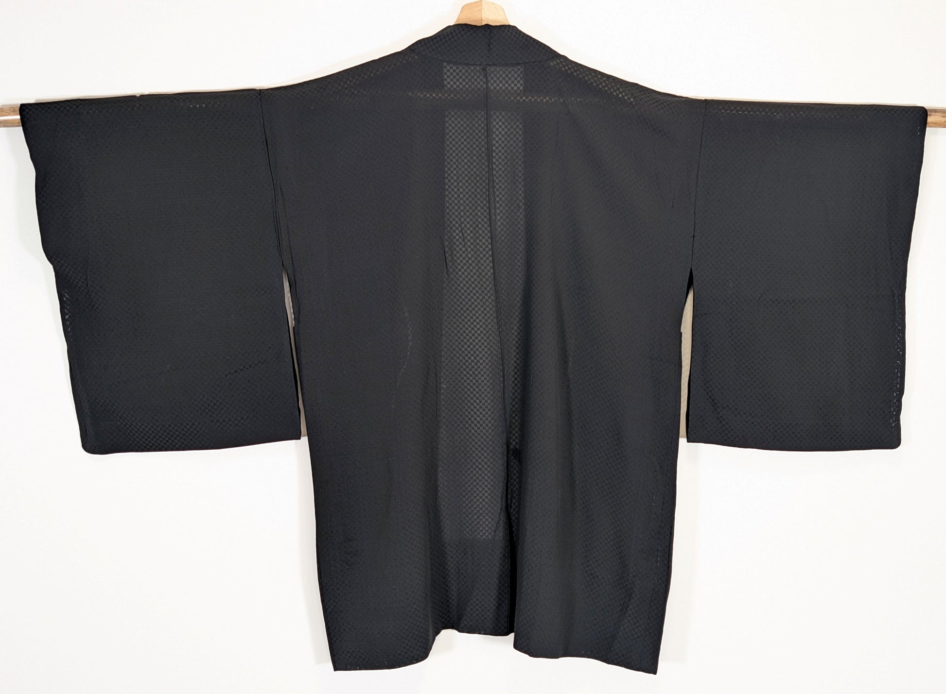 Vue de dos d’un haori japonais léger de type usubaori en soie noire monsha, étoffe transparente à damier ichimatsu.