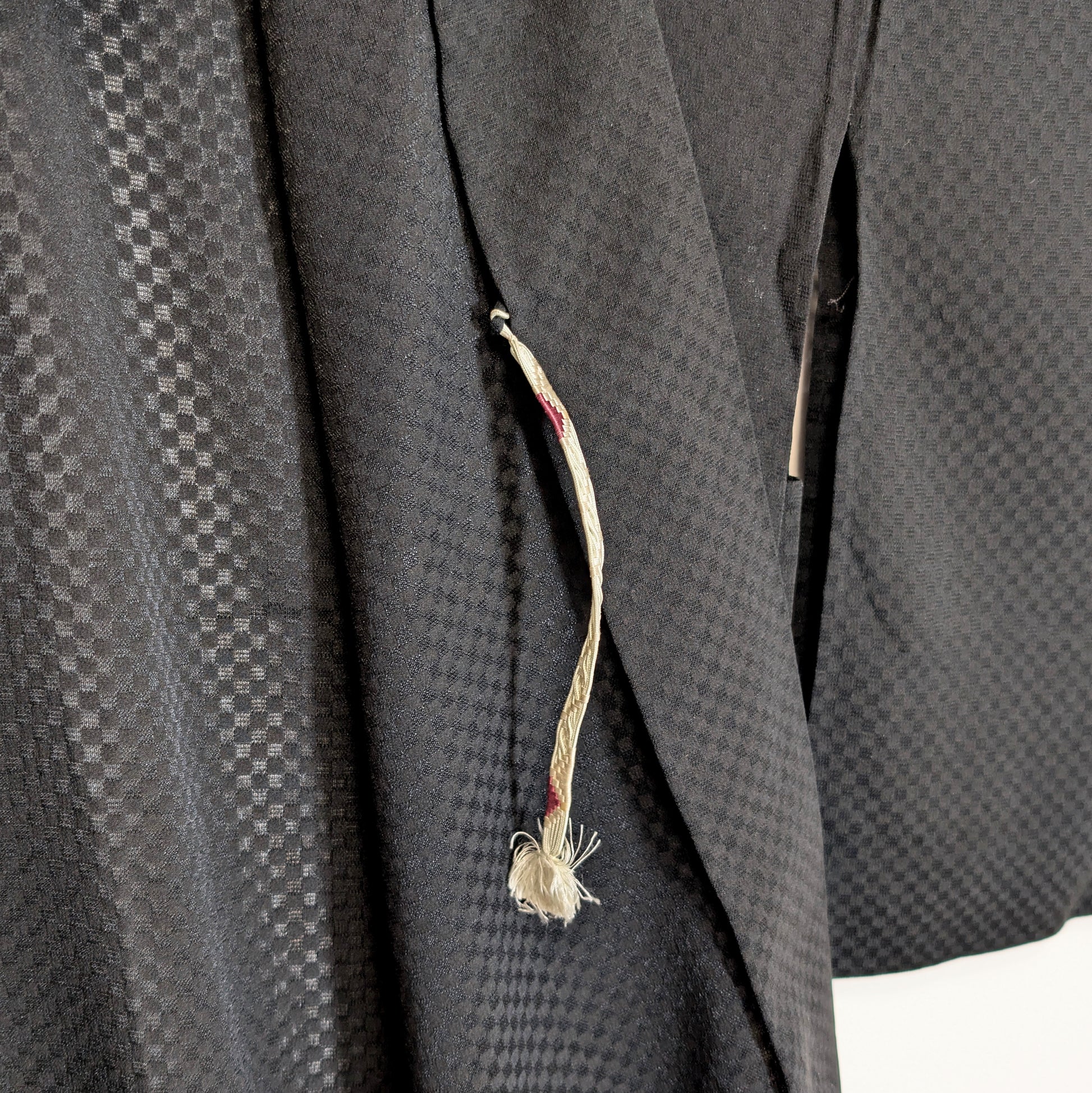 Détail du himo d’un haori japonais noir en soie monsha, avec motif ichimatsu discret et texture légère traditionnelle.