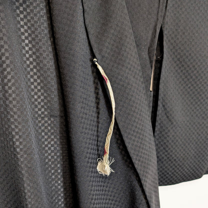 Détail du himo d’un haori japonais noir en soie monsha, avec motif ichimatsu discret et texture légère traditionnelle.