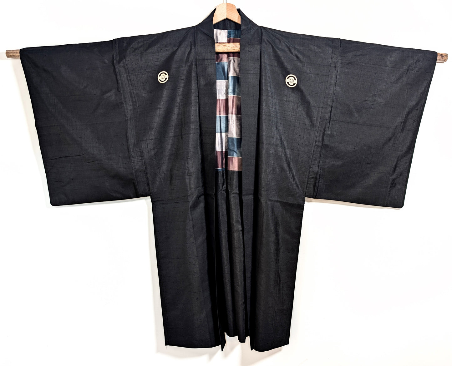 Vue de face d’un haori japonais noir en soie, veste traditionnelle ornée de kamon