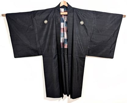 Vue de face d’un haori japonais noir en soie, veste traditionnelle ornée de kamon