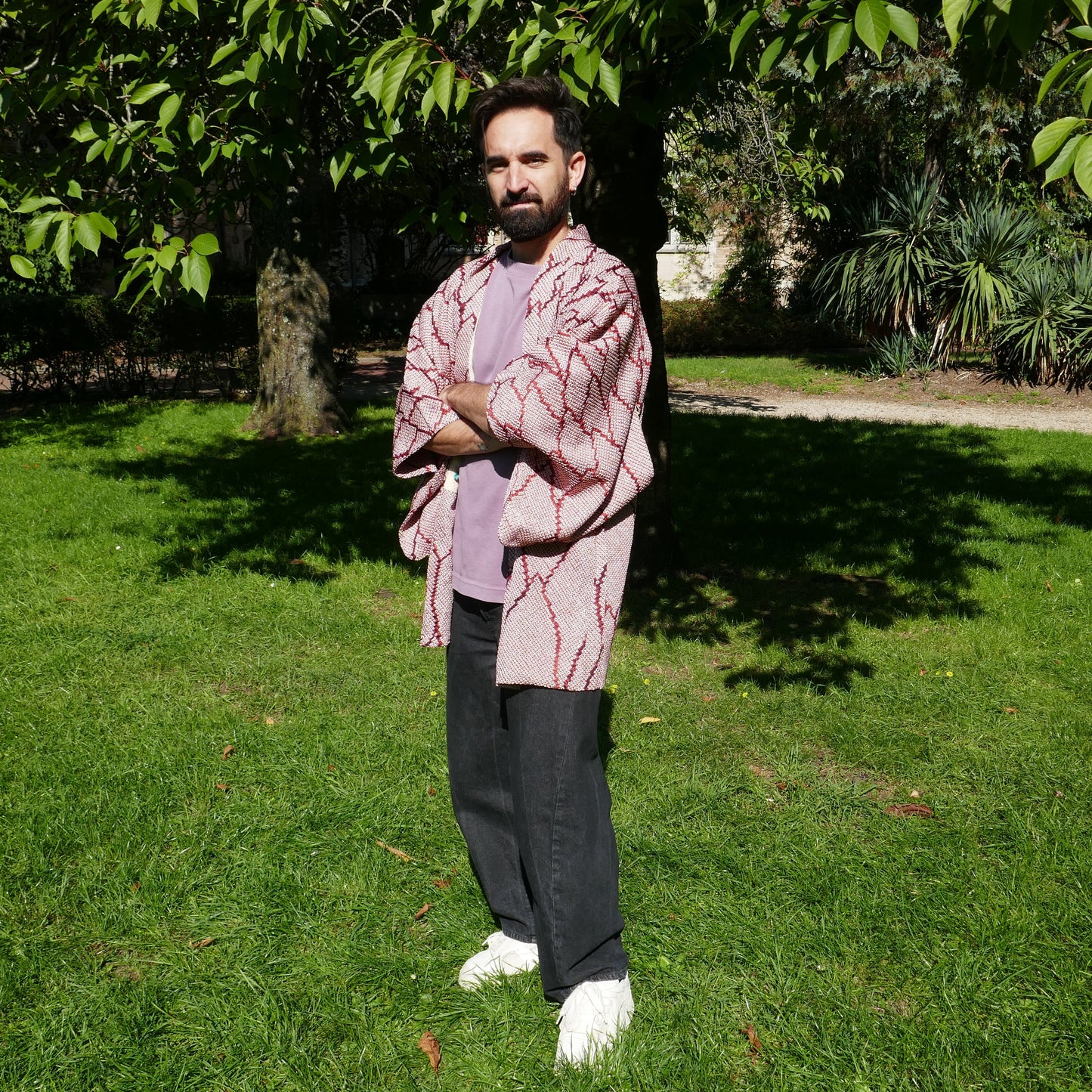 Tôma en veste kimono traditionnelle haori vintage japonais en soie, motif shibori rouge grenat, dans un parc à Paris.