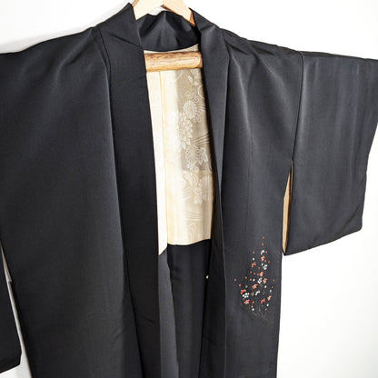 Haori japonais en soie noire habutae, veste kimono élégante avec fleurs de prunier ume rouges, blanches et dorées, doublure ivoire visible.