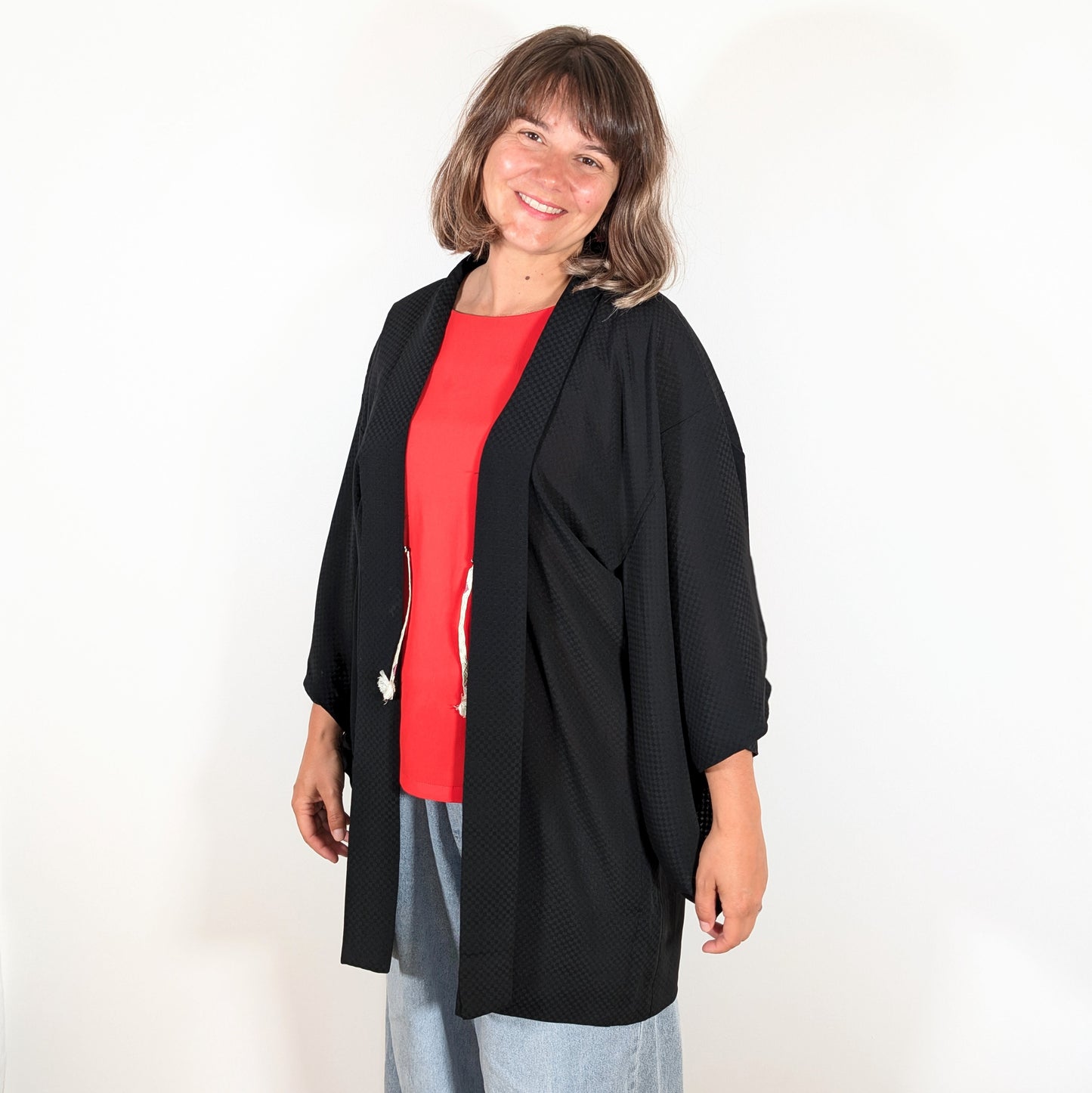 Haori japonais authentique en soie noire monsha porté sur une tenue contemporaine, veste kimono légère à motif ichimatsu.