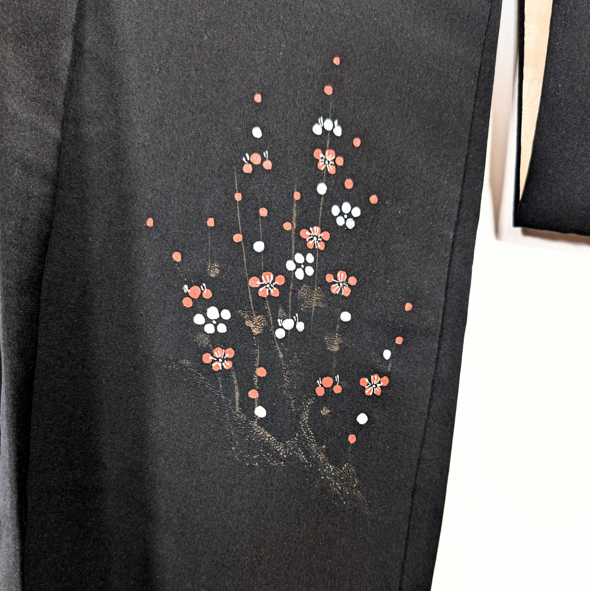 Détail du motif ume sur haori noir chic, fleurs de prunier rouges et blanches avec branches dorées sur soie japonaise.