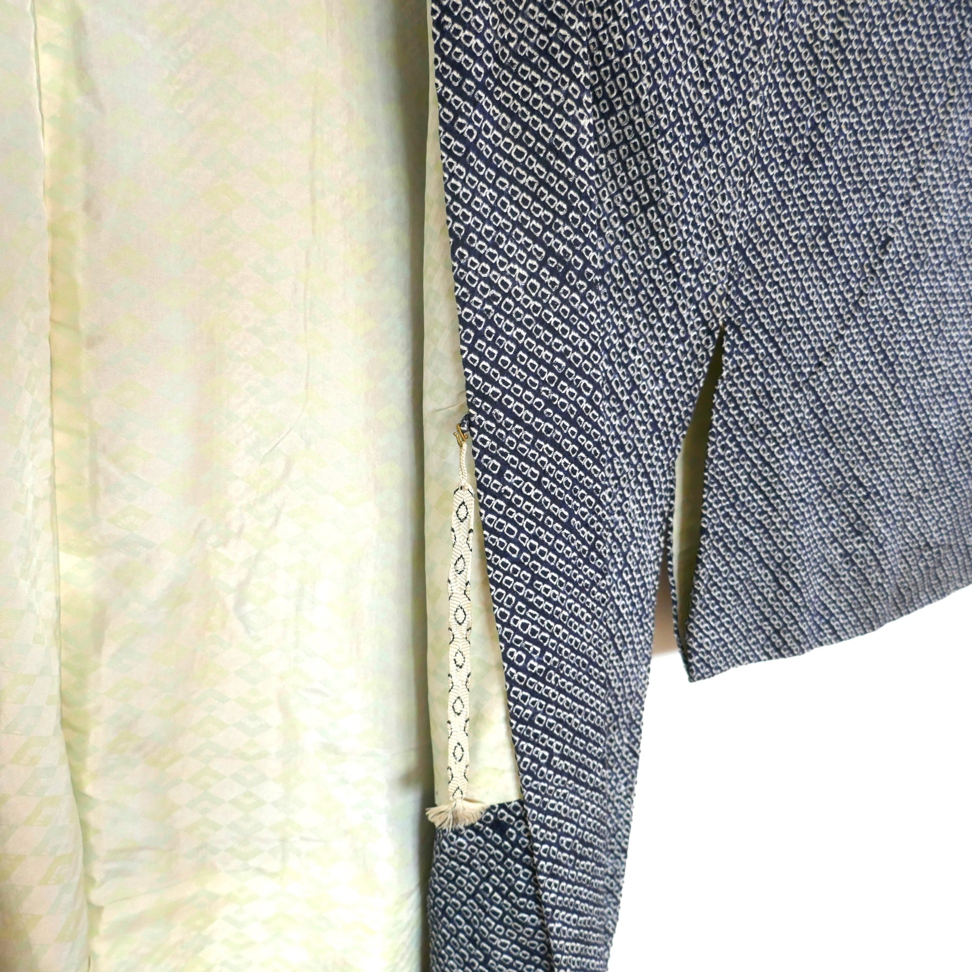 Gros plan sur l’attache intérieure haori himo d’un haori en soie, avec aperçu de la doublure à motifs d’éventails.