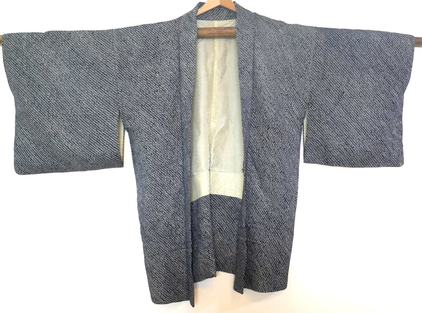 Vue entière d’un haori vintage en shibori bleu nuit suspendu sur cintre.