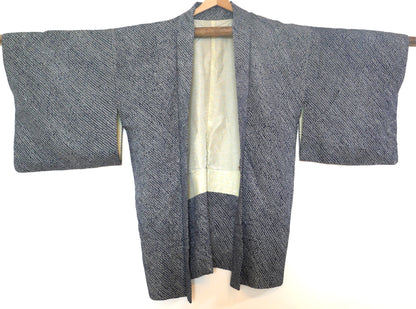 Vue entière d’un haori vintage en shibori bleu nuit suspendu sur cintre.