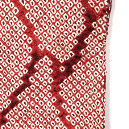 Gros plan du motif shibori couleur grenat sur soie, rendant visible une petite tâche à l'arrière de la manche.