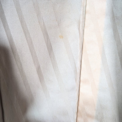 Gros plan sur la doublure en soie ivoire à rayures satinées ton sur ton d'un haori japonais vintage en brocart noir et cuivre.