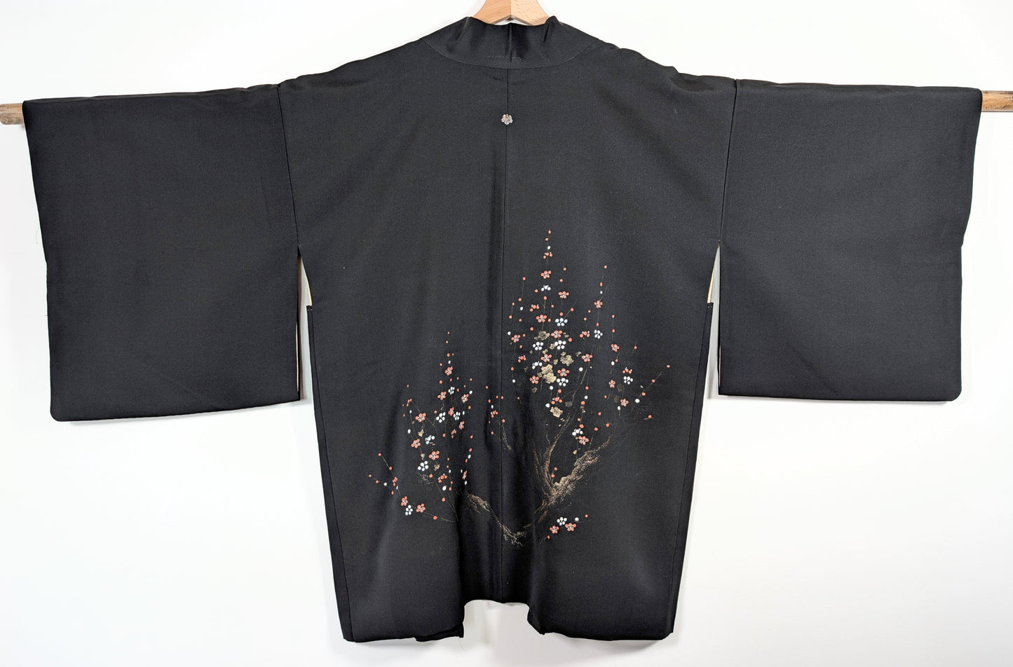 Dos complet d’un haori vintage du Japon en soie noire discrètement brillante, décor de fleurs ume rouges, blanches et dorées.