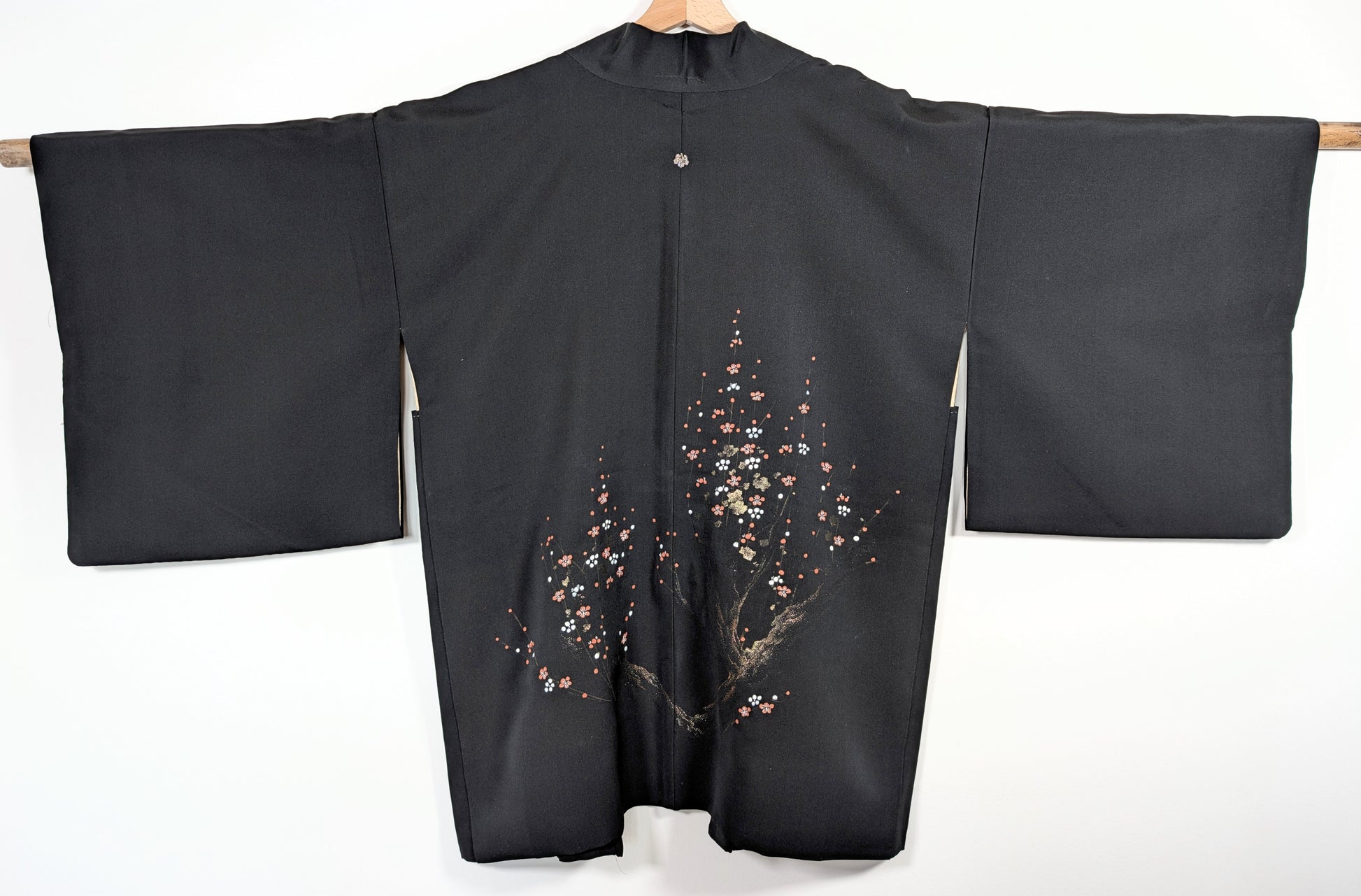 Dos complet d’un haori vintage du Japon en soie noire discrètement brillante, décor de fleurs ume rouges, blanches et dorées.