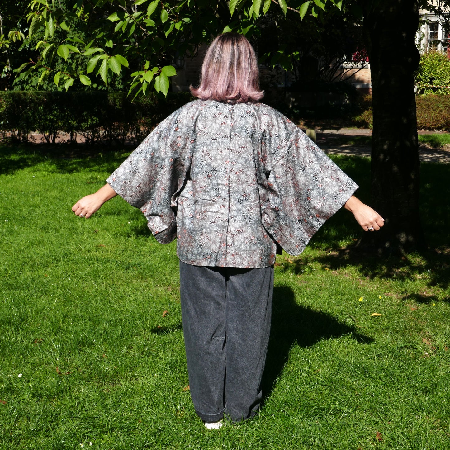 Mikan de dos en veste kimono traditionnelle haori vintage japonais en soie, gris métalisé avec momiji, dans un parc à Paris.