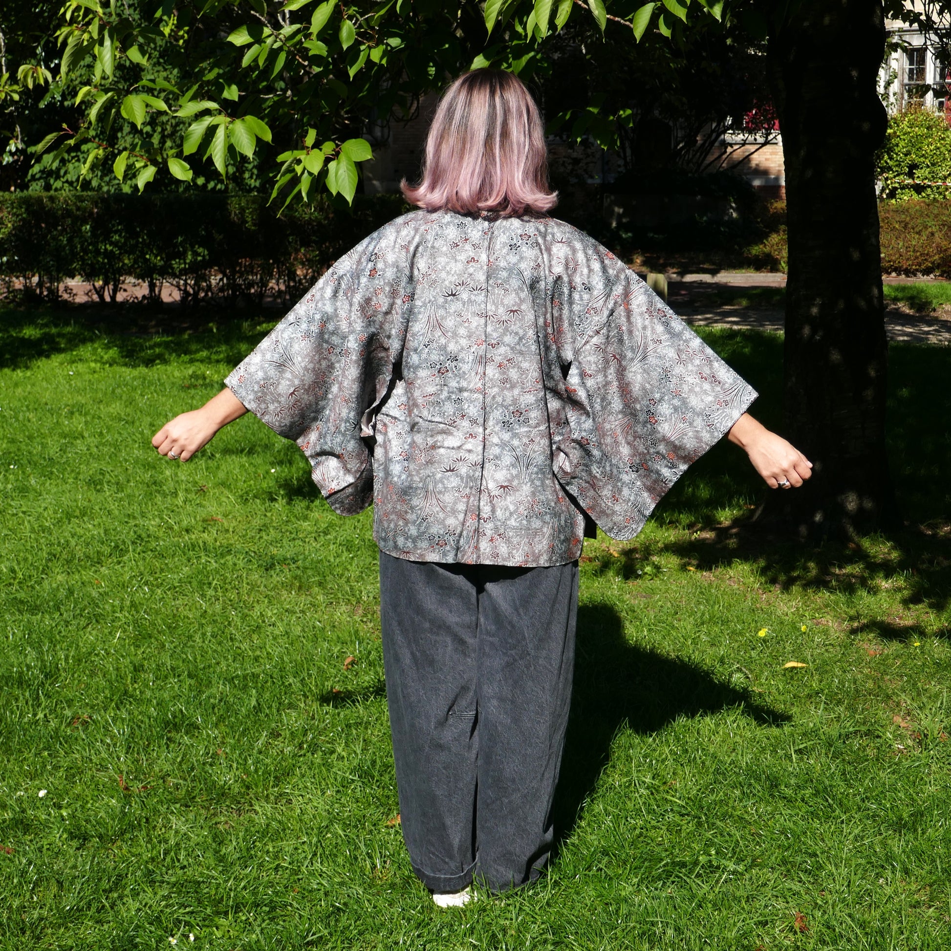 Mikan de dos en veste kimono traditionnelle haori vintage japonais en soie, gris métalisé avec momiji, dans un parc à Paris.