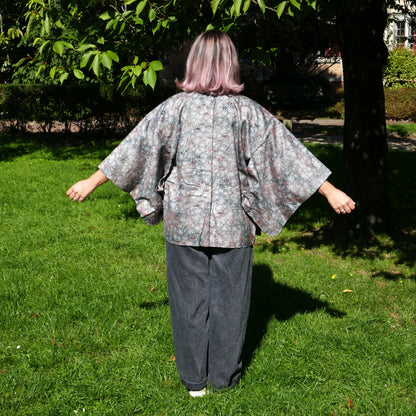 Mikan de dos en veste kimono traditionnelle haori vintage japonais en soie, gris métalisé avec momiji, dans un parc à Paris.