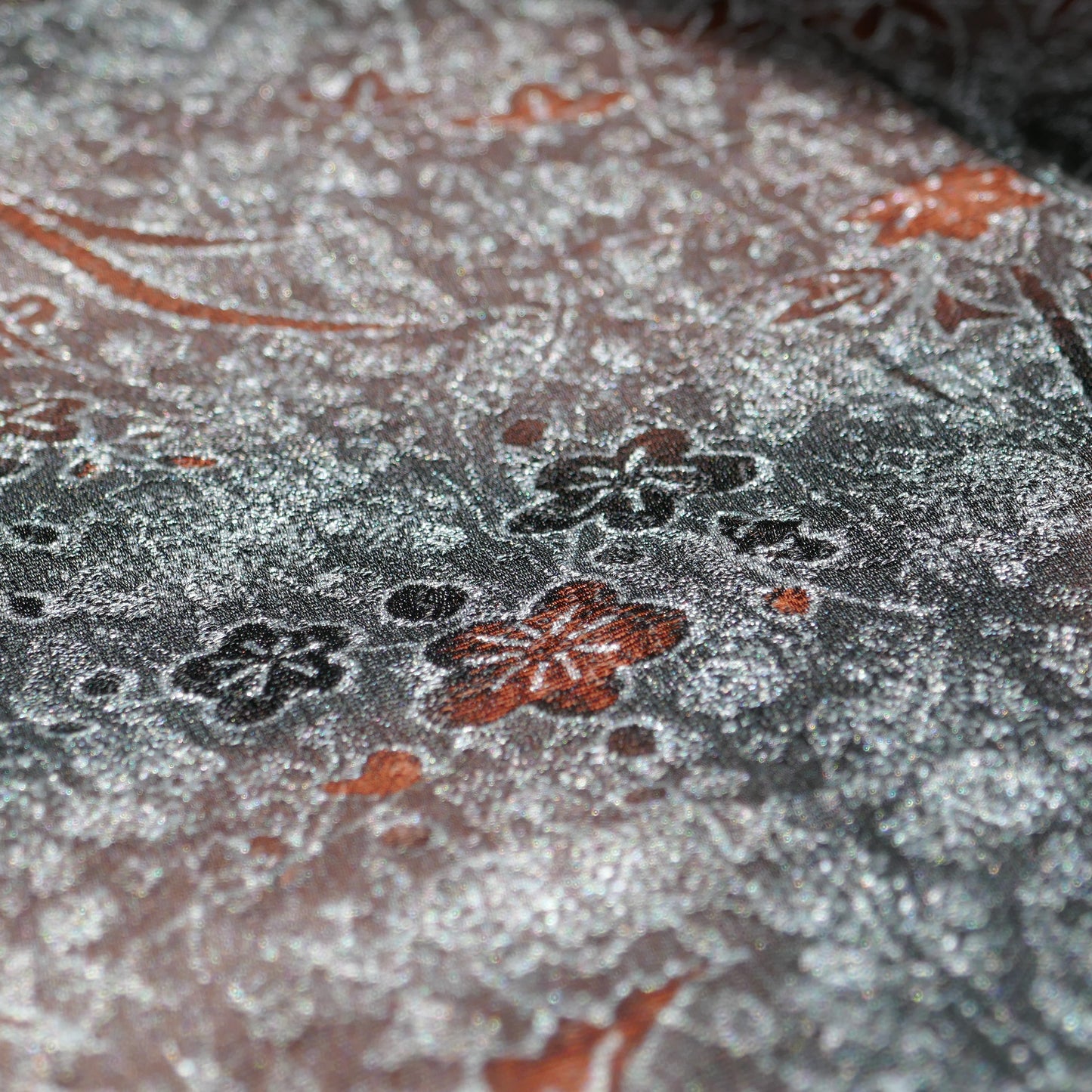 Détail du tissu gris métallisé avec motifs floraux momiji noirs et rouille
