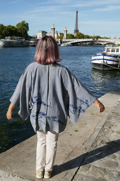Femme portant un haori vintage en soie, veste kimono traditionnelle japonaise, motif shibori bleu et pin 松 stylisé dans le dos, photo à Paris.