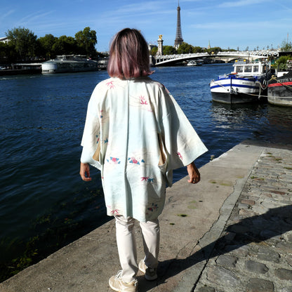 Vue de dos de Mikan en haori vintage en soie, veste kimono traditionnelle japonaise claire, décorée de fleurs et bambous, devant la tour Eiffel.