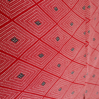 Gros plan du tissu extérieur du haori, montrant les motifs losange en rouge, blanc et noir typiques de l’artisanat japonais.