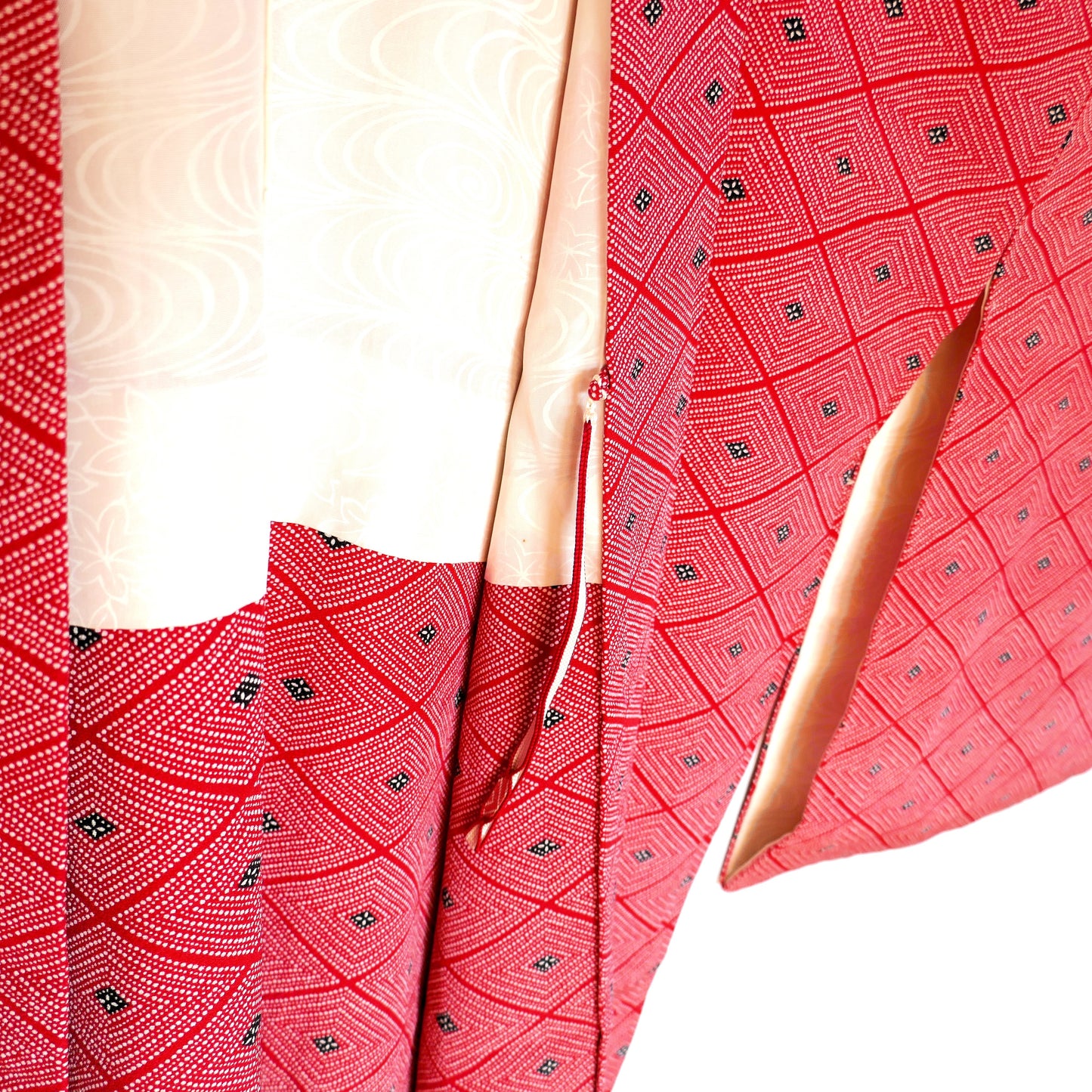 Détail de l’intérieur d’un haori vintage rouge montrant l’attache himo et la doublure en soie ivoire à motifs.