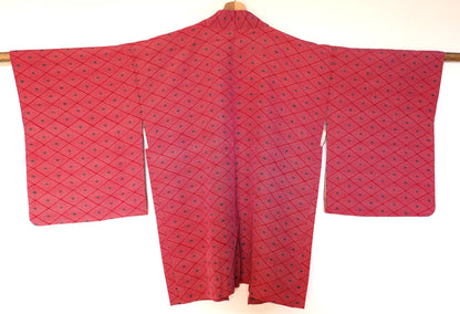  Vue de dos complète d’un haori vintage suspendu, en soie rouge à motifs géométriques losange (菱形).