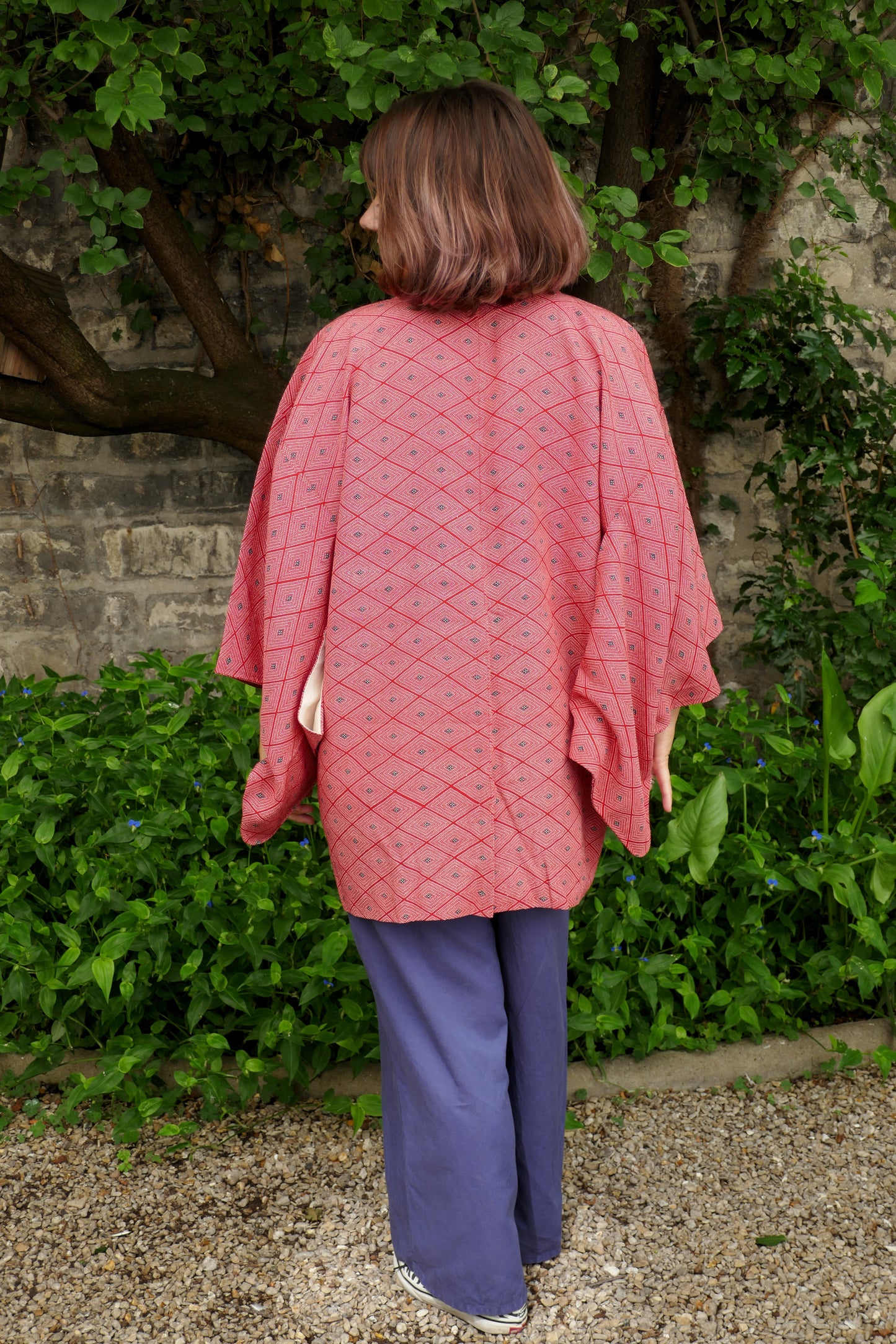 Vue de dos complète d’un haori vintage suspendu, en soie rouge à motifs géométriques losange (菱形).