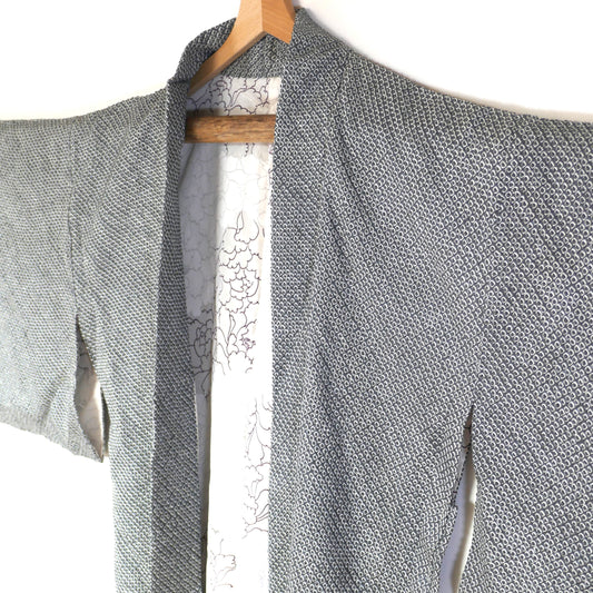 Haori japonais vintage en soie grise motif shibori 絞り, vue en diagonale avec doublure blanche.