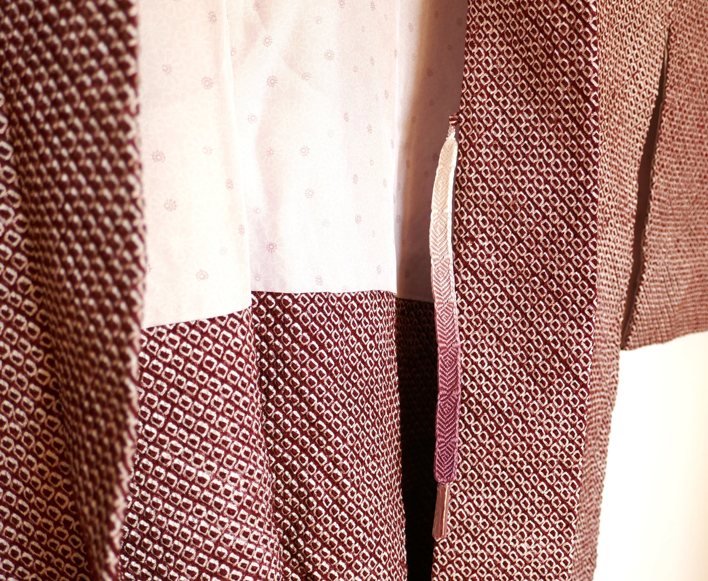 Détail de l’ouverture intérieure du haori bordeaux montrant la doublure soyeuse à fleurs kiku et le haori himo.